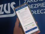 Smartfon w dłoni na tle Loga ZUS