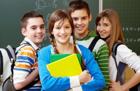 Stojące dwie uczennice i dwóch uczniów w klasie