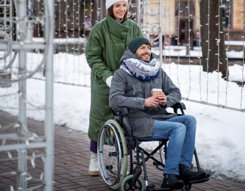 Kobieta pchająca mężczyznę na wózku inwalidzkim
