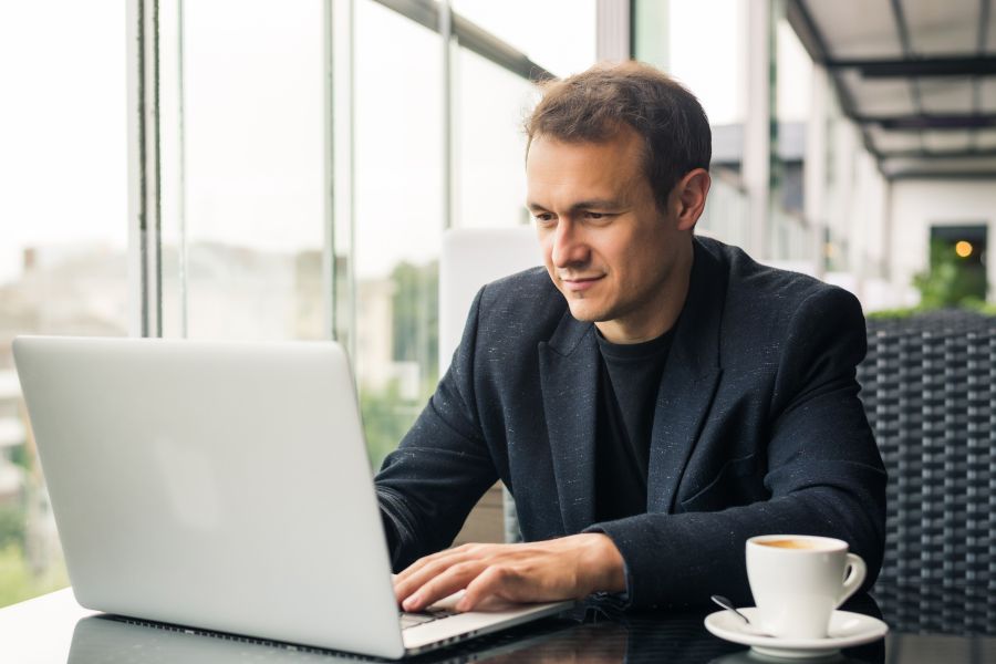 Mężczyzna siedzący przy stole z laptopem