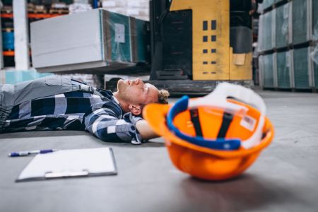 leżący człowiek na podłodze obok niego kask