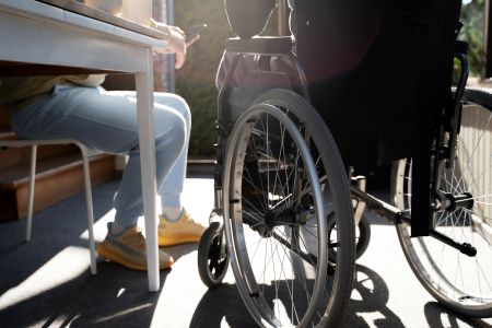 Osoba siedząca na krześle przy stoliku a obok niej osoba na wózku inwalidzkim