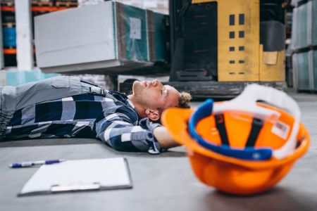 mężczyzna leżący na podłodze, obok niego kask