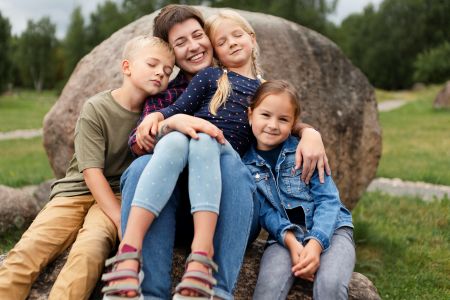 Mama z trójką dzieci siedząca na kamieniu
