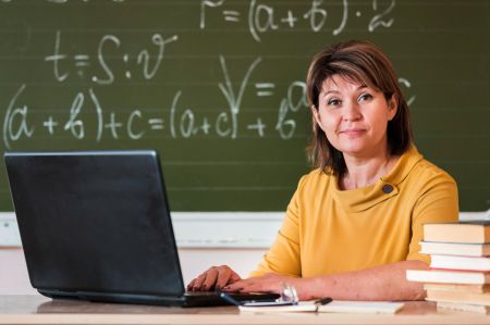 Nauczyciel siędzący przy biurku z laptopem