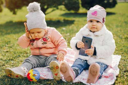 Dwójka dzieci bawiących się telefonami komórkowymi