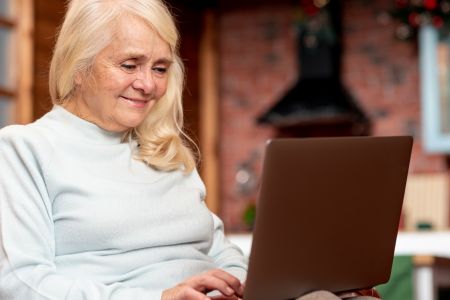 Starsza pani pisząca na laptopie