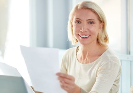 Starsza pani trzymająca w dłoniach kartkę